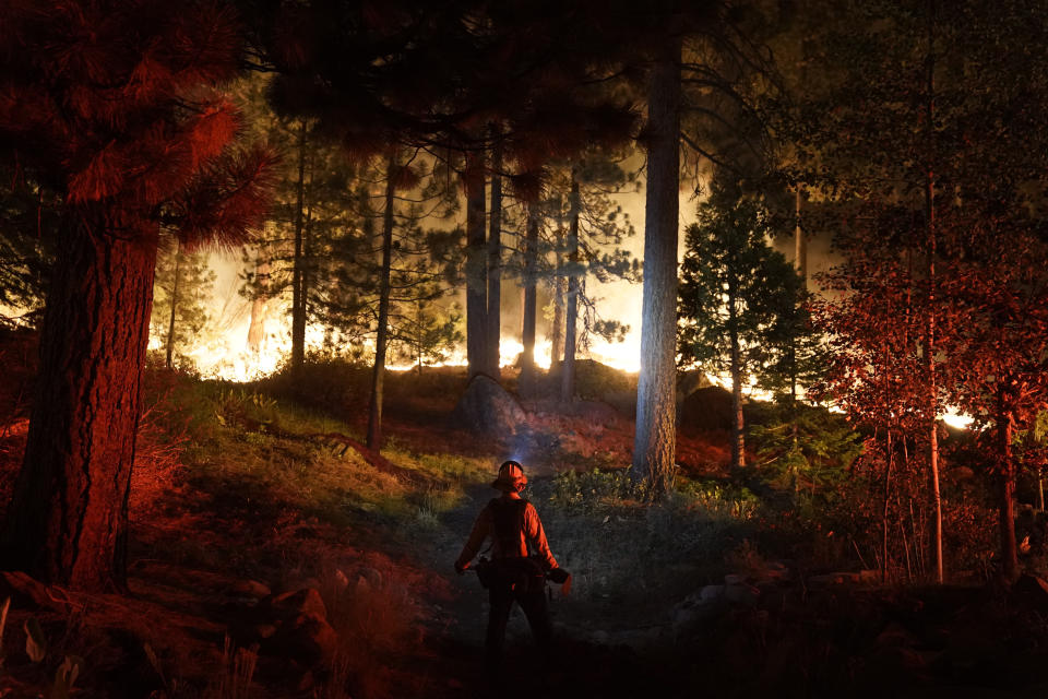 FILE - In this Monday, Aug. 30, 2021 file photo, a firefighter monitors the Caldor Fire burning near homes in South Lake Tahoe, Calif. As the winds returned this week, the Caldor Fire roared over the Sierra crest and bore down on the southern end of Lake Tahoe. Last week, managers overseeing the fight against the massive wildfire scorching California's Lake Tahoe region thought they could have it contained by the start of this week. Instead, on Monday, Aug. 30, 2021, the Caldor Fire crested the Sierra Nevada, forcing the unprecedented evacuation of all 22,000 residents of South Lake Tahoe. (AP Photo/Jae C. Hong, File)