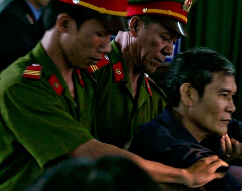 FILE PHOTO: Vietnamese dissident priest Father Thadeus Nguyen Van Ly (R) is escorted by police as he faces a court in Vietnam's central Hue City