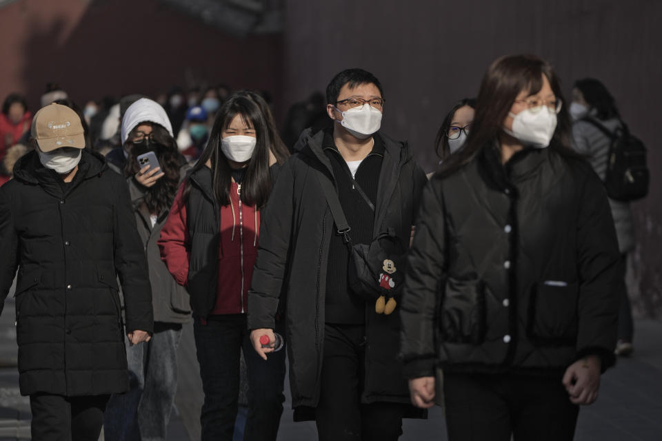 FILE - People wearing face masks walk along a street in Beijing, Friday, Jan. 6, 2023. China has suspended or closed the social media accounts of more than 1,000 critics of the government’s policies on the COVID-19 outbreak, as the country moves to further open up. (AP Photo/Andy Wong)