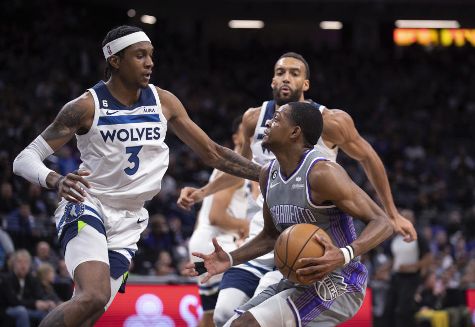 Minnesota Timberwolves forward Jaden McDaniels (3) and center Rudy Gobert (27) double-team Sacramento Kings guard De'Aaron Fox (5) during the second half of an NBA basketball game in Sacramento, Calif., Saturday, March 4, 2023. The Timberwolves won 138-134. (AP Photo/José Luis Villegas)