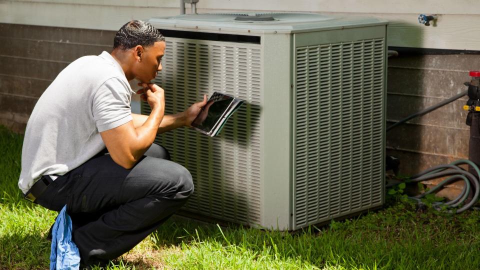 Home inspector, repairman, adjuster examines air conditioner units at a customer's home.
