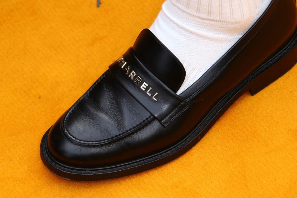 Pharrell Williams wearing custom black leather loafers featuring his name on the front strap. - Credit: Shutterstock