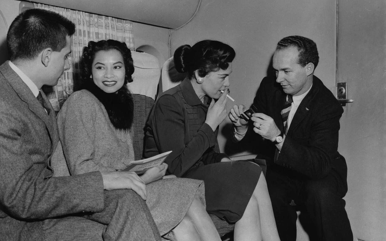 Passengers light up on a Transocean Air lines flight in the mid-1950s - Getty