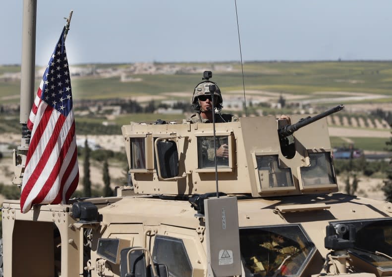 A U.S. soldier sits in an armored vehicle on a road leading to the tense front line with Turkish-backed fighters, in Manbij, north Syria, Wednesday, April 4, 2018. President Donald Trump expects to decide "very quickly" whether to remove U.S. troops from war-torn Syria, saying their primary mission was to defeat the Islamic State group and "we've almost completed that task." (AP Photo/Hussein Malla)