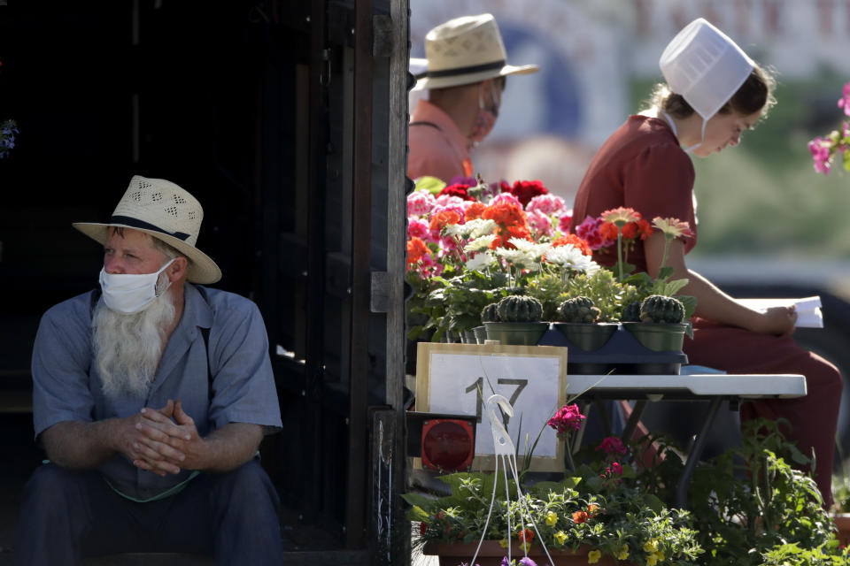 Vendors wait for customers at a drive-thru farmers market Saturday, May 2, 2020, in Overland Park, Kan. The market has moved from its usual home to a sprawling parking lot allowing for people to spread out and shop from their cars as a measure to stem the spread of COVID-19. (AP Photo/Charlie Riedel)