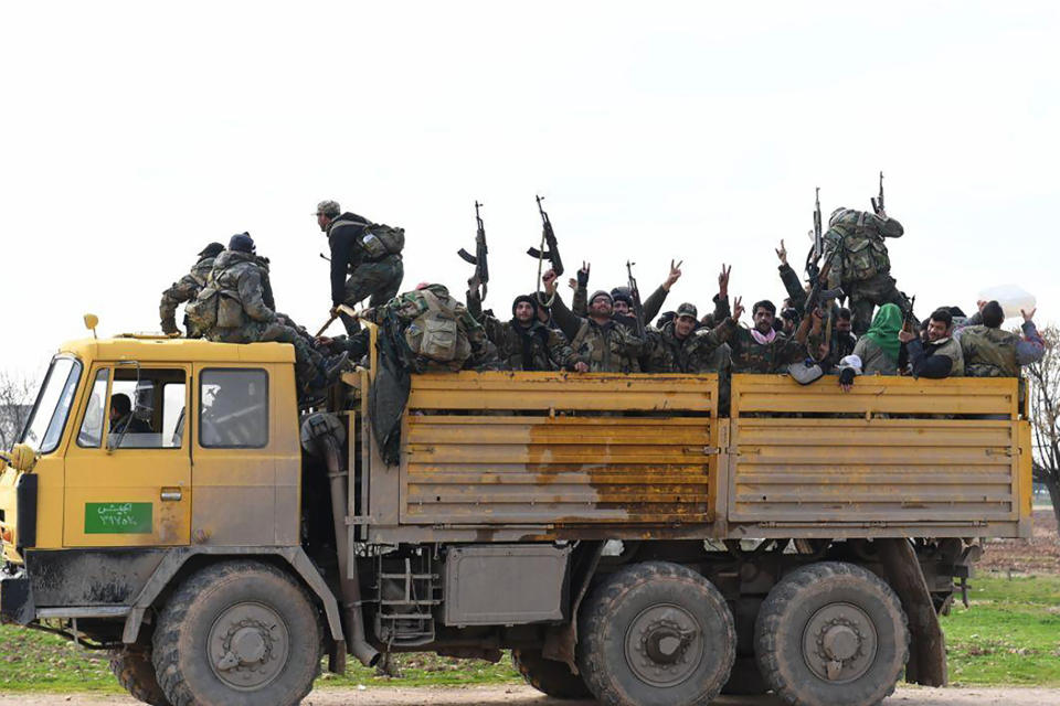 In this photo released Wednesday Feb. 5, 2020 by the Syrian official news agency SANA, shows Syrian government forces in a truck holding up their rifles and flashing victory signs, as they enter the village of Tel-Sultan, in Idlib province, northwest Syria. State media and opposition activists say Turkey has sent more reinforcements into northwestern Syria, setting up new positions in an attempt to stop a government offensive on the last rebel stronghold in the war-torn country. (SANA via AP)