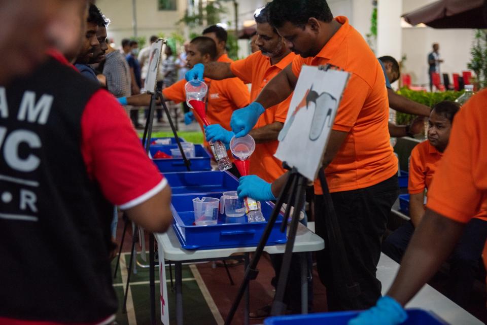 Filling stations are manned by volunteers at Migrant Workers' Centre. They work quickly to transfer the sanitisers into the recipient’s clean, and labelled bottles. (PHOTO: Temasek)