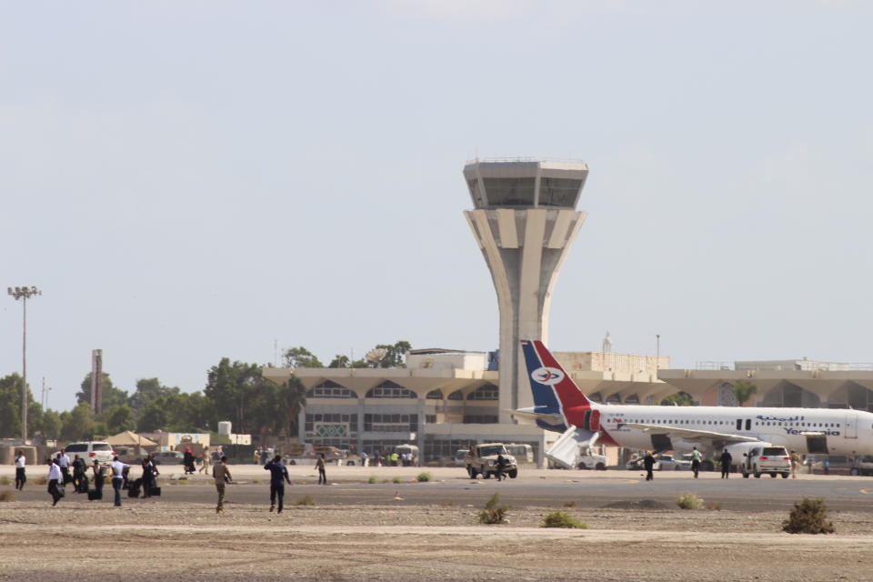 Bystanders stand near the runway of Yemen southern city of Aden’s airport shortly after an explosion hit as a government plane landed, Wednesday, Dec. 30, 2020. The blast struck the airport building shortly after a Yemenia airlines plane carrying the newly formed Cabinet landed. No one on the government plane was hurt. (AP Photo/Wael Qubady)