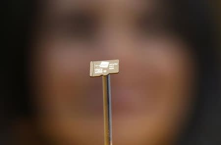 A woman looks at a data chip containing encryption codes for mobile and landline phones at the booth of Secusmart during the CeBIT trade fair in Hanover March 8, 2014 REUTERS/Wolfgang Rattay