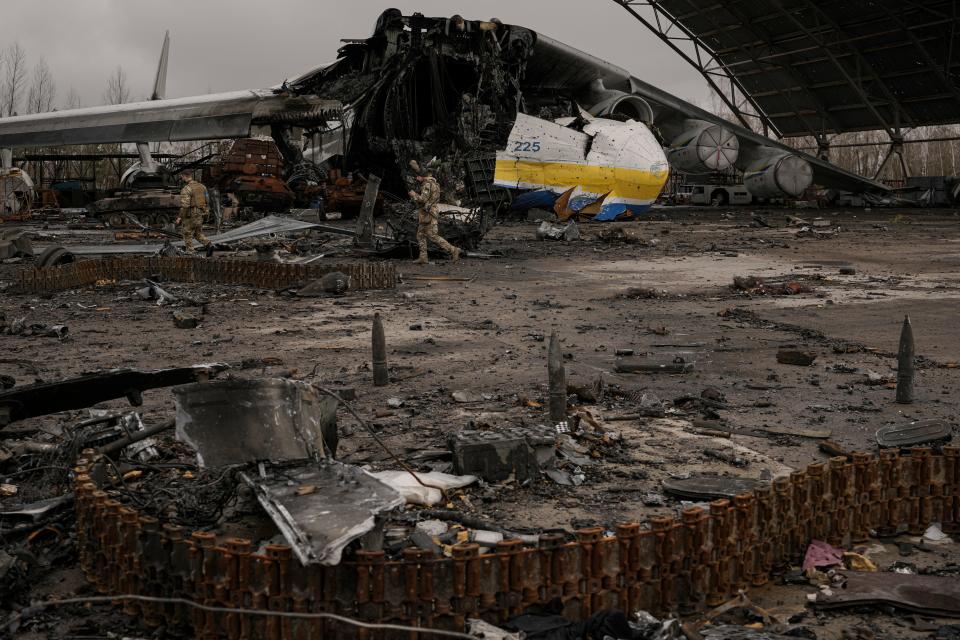 Ukrainian servicemen walk by the destroyed Antonov An-225 Mriya aircraft.