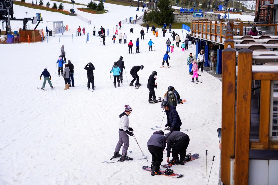 Skiers and snowboarders trek to their next slope near the main lodge on Saturday, Dec. 30, 2023, at Perfect North Slopes in Lawrenceburg, Ind.