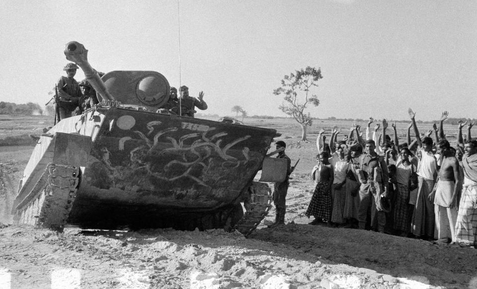 FILE - In this Dec. 14, 1971, file photo, East Pakistani villagers cheer at an advancing Indian army tank, manufactured by the Russians, as it moves towards Bogra, East Pakistan. Indian army tanks with mounted infantry had broken through heavily defended East Pakistani positions. Bangladesh is celebrating 50 years of independence this year. (AP Photo, File)