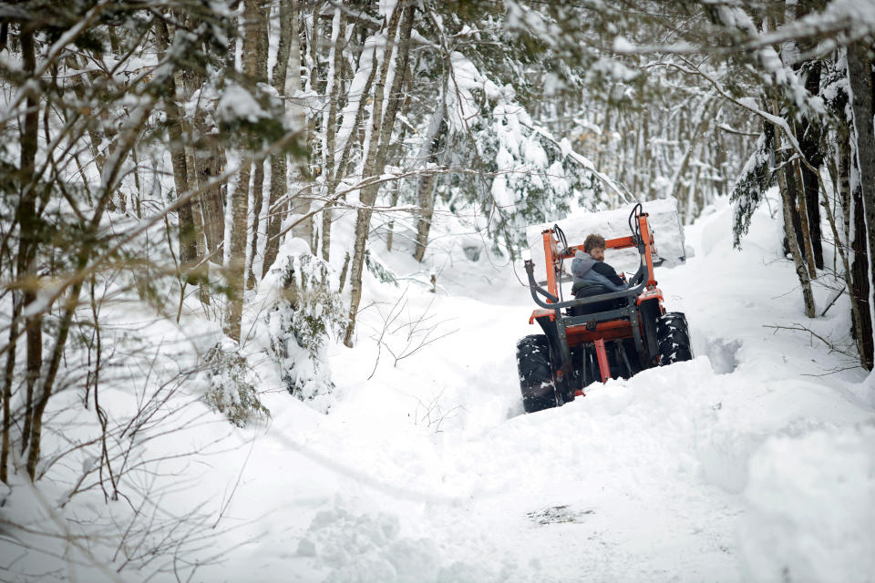 A resident uses a small front end loader to clear snow in Windsor, Mass., Wednesday, March 15, 2023, the day after a snow storm. (Stephanie Zollshan/The Berkshire Eagle via AP)