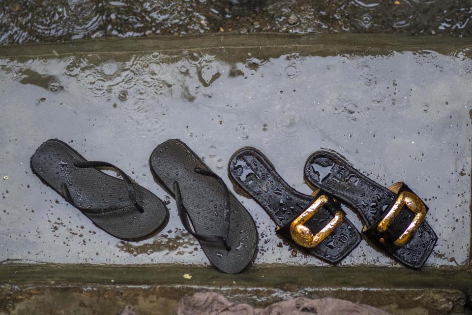 Sandals sit in the rain outside Vanessa Emedy 's dwelling in Goma, Democratic Republic of the Congo, Thursday March 31, 2022. The night of her late husband Godefroid Kamana's burial, extended family members came to the family home where Vanessa had just begun her period of mourning. "They didn't wait the 40 days," she lamented. "I was stripped of everything, of all my possessions." (AP Photo/Moses Sawasawa)