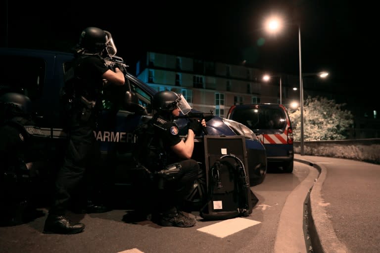 French police take cover behind their vehicles after coming under fire in Persan, near Beaumont-sur-Oise, on July 23, 2016, following clashes between residents and police over the death of Adama Traore