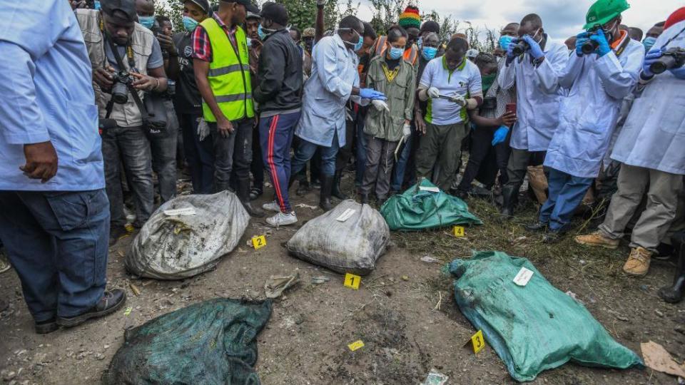 Investigators take pictures of body bags retrieved from a Nairobi rubbish dump