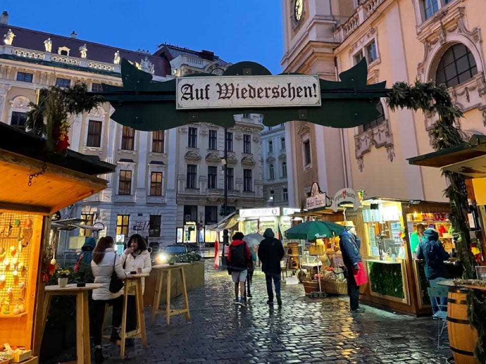 Photo of a night holiday market in Vienna with lit-up stands for sellers and people walking on cobblestone streets