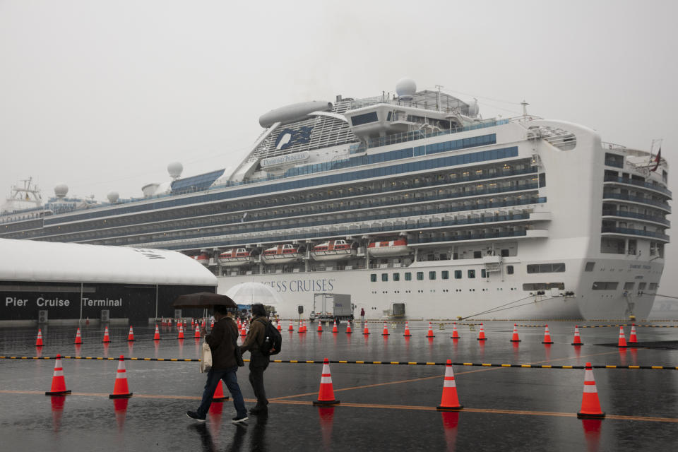 Visitors walk past the quarantined Diamond Princess cruise ship in Yokohama, near Tokyo. Americans who have not testes positive for the virus will be flown back home on chartered flights Sunday, but will face another two-week quarantine. (Photo: ASSOCIATED PRESS)