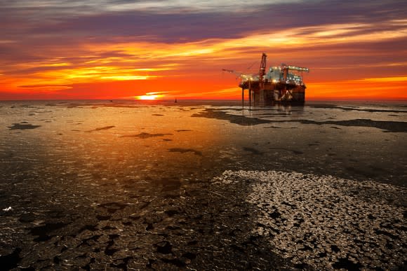 An offshore oil rig at sunrise in the frozen sea.