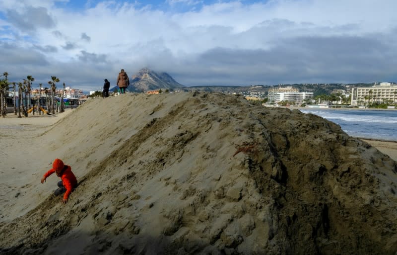 A child plays on a huge sand shaft built to protect the Arenal Beach ahead of the upcoming storm "Gloria", in Javea near Alicante