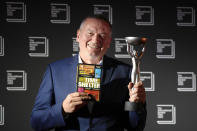 Bulgarian writer Georgi Gospodinov holds up his book "Time Shelter" translated from Bulgarian by Angela Rodel after winning The International Booker Prize 2023, in London, Tuesday, May 23, 2023. (AP Photo/Kirsty Wigglesworth)