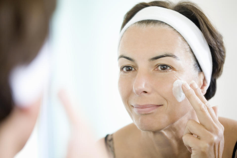 Mature woman applying moisturizer