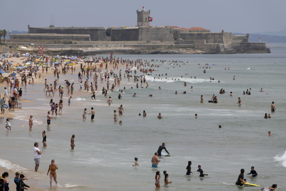 Beachgoers enjoy the water at Carcavelos Beach, outside Lisbon, Tuesday, July 12, 2022. Portugal is experiencing a heatwave that led the government to declare a state of alert from Monday through Friday due to the heightened risk of forest fires. Temperatures are forecast to reach 46 degrees Celsius (115 Fahrenheit) in some parts of the country by Wednesday. (AP Photo/Armando Franca)
