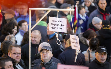 FILE PHOTO: People hold up a mock hangman's gallows with a sign reading 'Reserved for Sigmar Gabriel' (L) and 'Reserved for Angela Merkel' as they gather for an anti-immigration demonstration organised by rightwing movement Patriotic Europeans Against the Islamisation of the West (PEGIDA) in front of the Palace Church in Dresden, Germany October 12, 2015. Sigmar Gabriel is the German minister of Economy. REUTERS/Hannibal Hanschke/File Photo