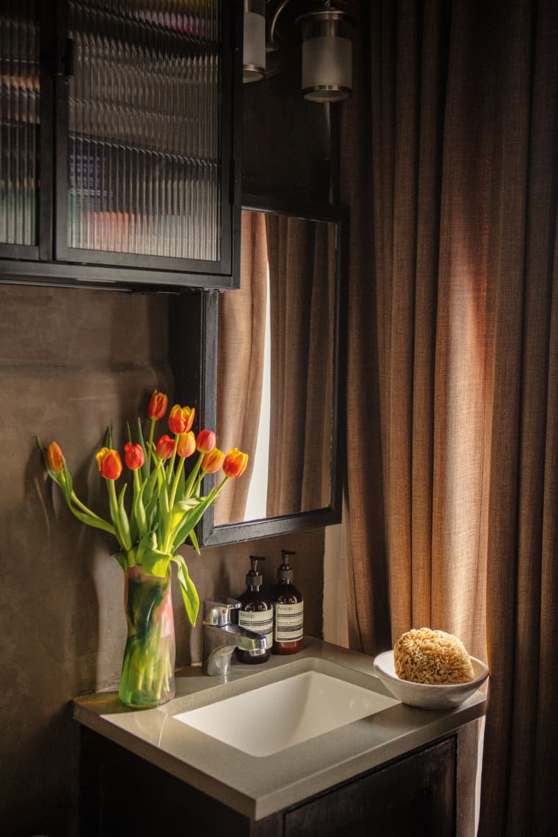 bathroom with brown curtain and warm light with fresh tulips by the sink