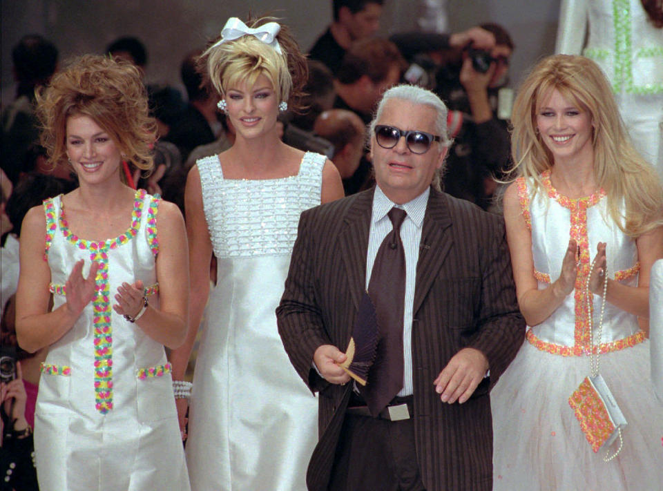 FILE - German designer Karl Lagerfeld joins models, from left, American Cindy Crawford, Canadian Linda Evangelista and Claudia Schiffer of Germany after the presentation of his 1996 spring-summer ready-to-wear fashion collection for Chanel in Paris on Oct. 19, 1995. Lagerfeld died in 2019 after dominating the fashion universe into his 80s. Come May 1, his legacy will be on display at the Met Gala and the starry fundraising party's companion exhibition at the Metropolitan Museum of Art's Costume Institute. (AP Photo/Remy de la Mauviniere, File)