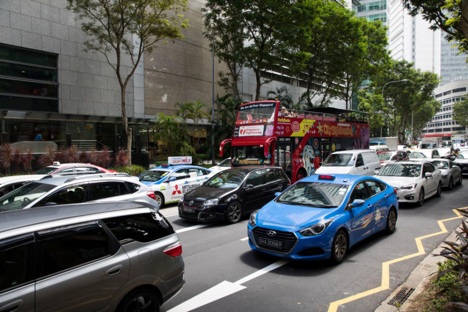 A tourist bus sits among other vehicles in traffic in the central business district of Singapore, illustrating a story on COE quota.