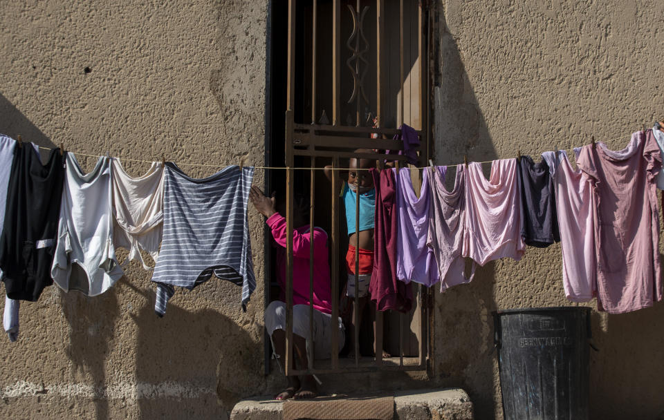 A mother and her child sit at the doorstep of their home, at densely populated Alexandra township in Johannesburg, South Africa, Thursday, April 16, 2020. South African President Cyril Ramaphosa extended the lockdown by an extra two weeks in a continuing effort to contain the spread of COVID-19 coronavirus. (AP Photo/Themba Hadebe)