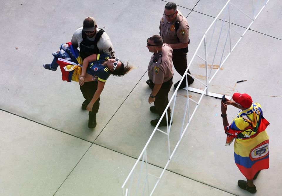 Un agente de policía transporta a un aficionado inconsciente. Según los informes, algunos asistentes estaban sufriendo por el calor y la humedad (Getty Images)