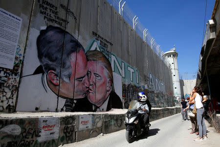 People look at a mural depicting U.S. President Donald Trump and Israel's Prime Minister Benjamin Netanyahu kissing each other in the West Bank city of Bethlehem October 29, 2017. REUTERS/Mussa Qawasma