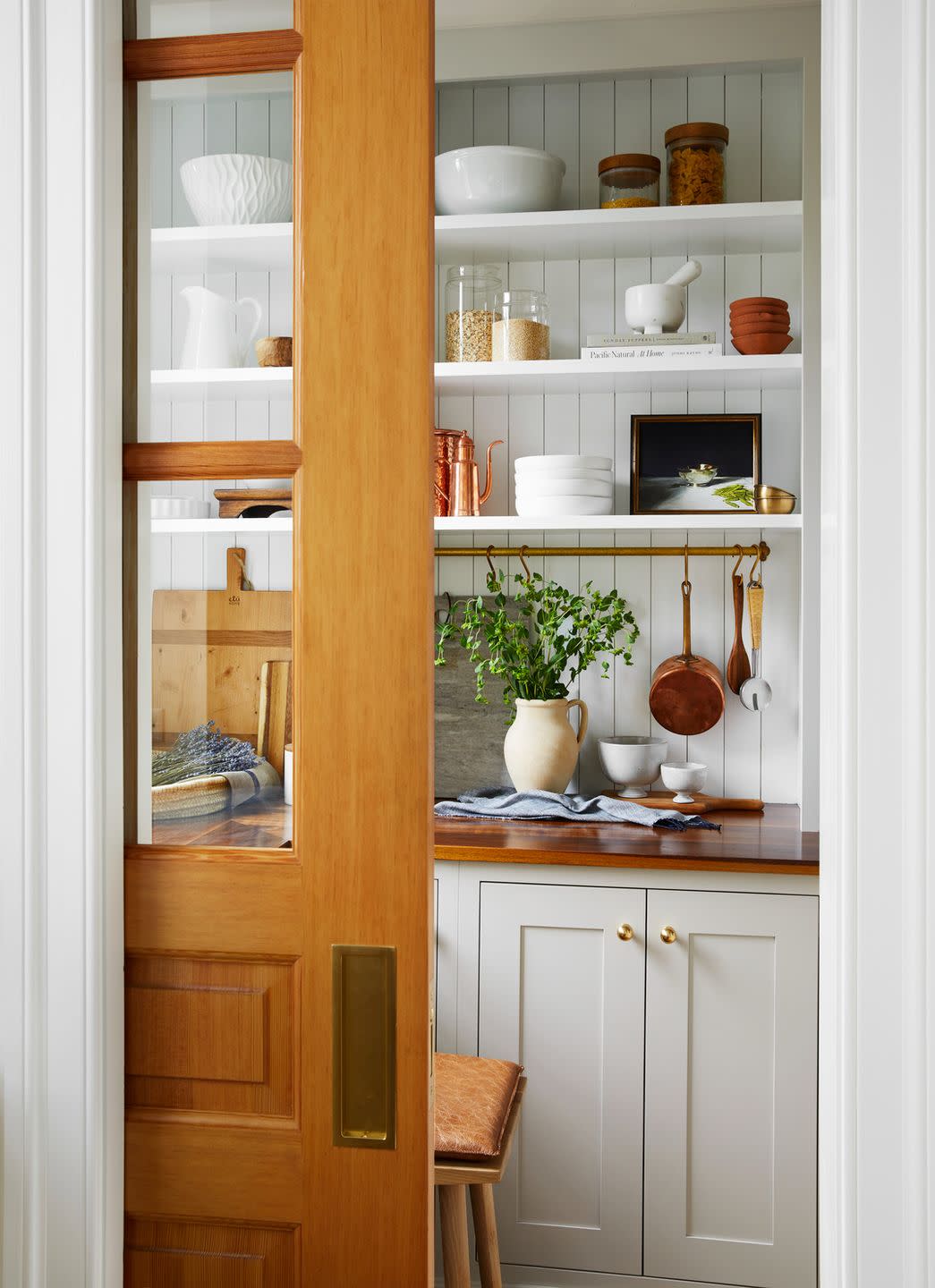 butcher block counter in the pantry and brass rail for hanging pots and utensils