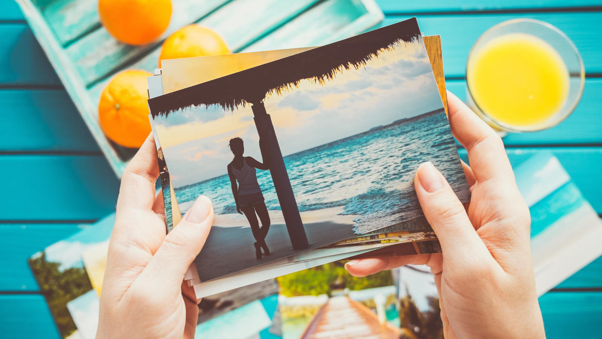 Hands holding a set of summer vacation photo prints