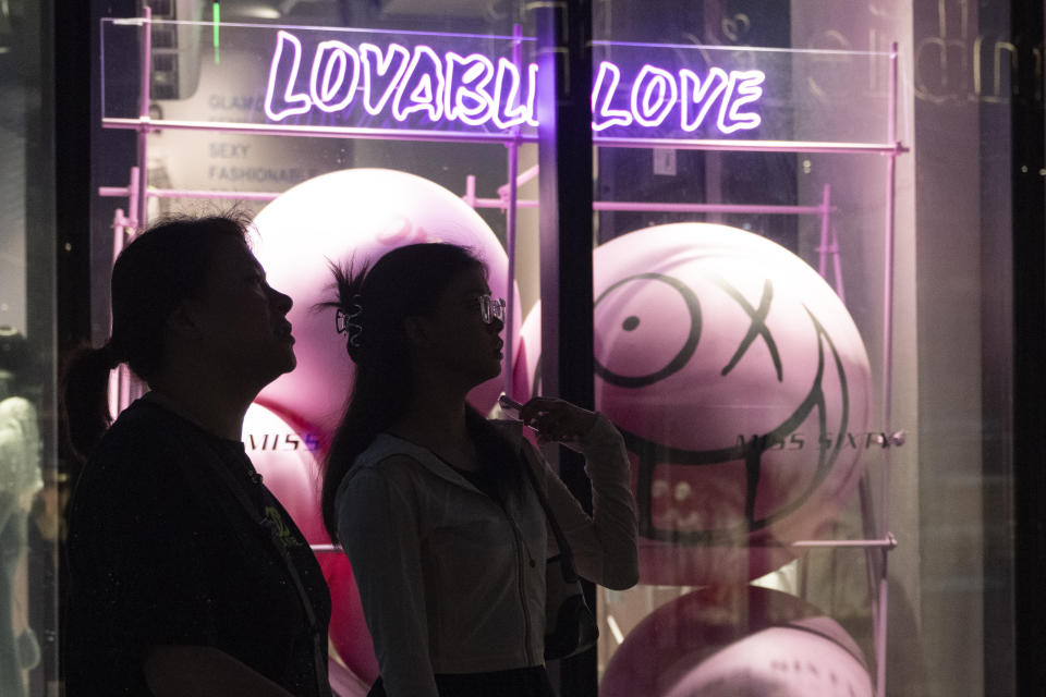 Shoppers walk past a window display at a mall in Beijing, Sunday, June 18, 2023. Chinese consumers snapped up billions worth of items in China's first major online shopping festival after emerging from the pandemic as merchants slashed prices, but analysts say that consumer confidence still remains weak. (AP Photo/Ng Han Guan)