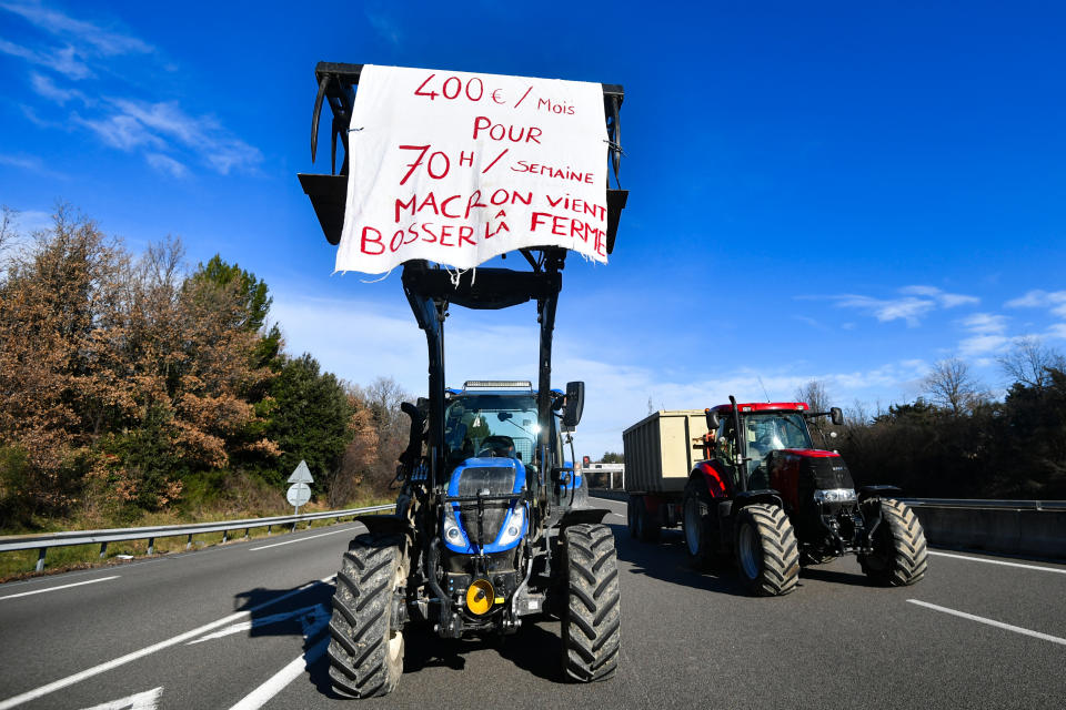 Un agriculteur montre une banderole sur son tracteur indiquant 