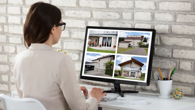 Rear View Of A Businesswoman Looking At House Photos On Computer In Office.