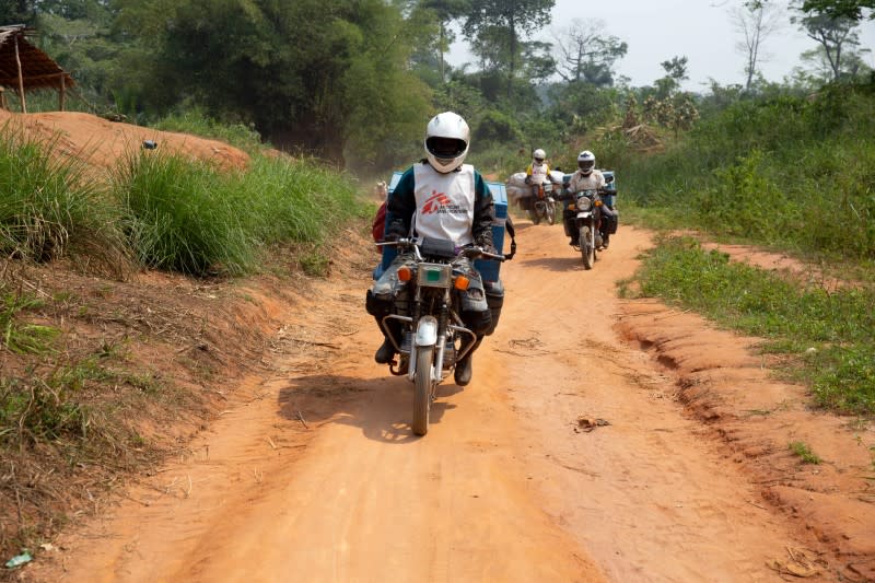 A motorcycle convoy carrying vials of measles vaccine and other supplies for medial NGO Doctors Without Borders rides down a sandy dirt road between Lisala and Boso-Manzi in Mongala province