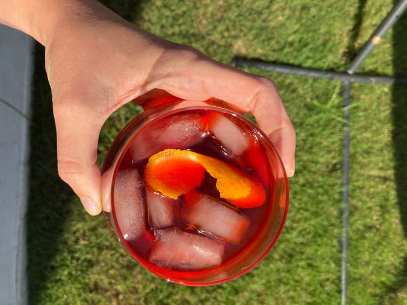 Someone holding glass of negroni poured from canned cocktail.
