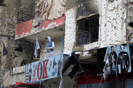 A man stands on a bullet-riddled building inside the Ain el-Hilweh refugee camp near Sidon, southern Lebanon, April 13, 2017. REUTERS/Ali Hashisho