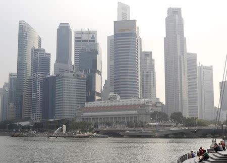 People sit along the Marina Bay area in the hazy skyline of Singapore March 4, 2014. REUTERS/Edgar Su