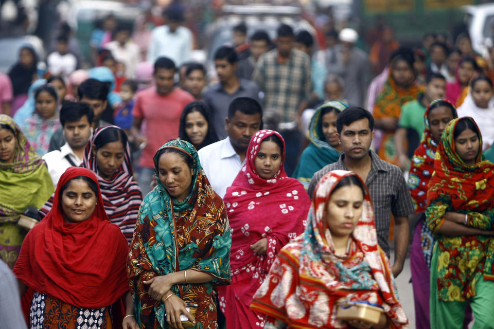 FILE - In this Feb. 13, 2014 file photo, Bangladeshi garment workers arrive for work early morning in Dhaka, Bangladesh. A survey of factory owners in Bangladesh has found that major fashion retailers that are closing shops and laying off workers in Europe and the U.S. also are canceling their sometimes already completed orders, as workers often go unpaid. A report released Friday, March 27, 2020, by Mark Anner, director of the Center of Global Rights, found the coronavirus crisis has resulted in millions of factory workers being sent home without the wages or severance they are owed. About 4.1 million people work in apparel factories in Bangladesh, the world's No. 2 garment exporter after China. (AP Photo/A.M. Ahad, File)