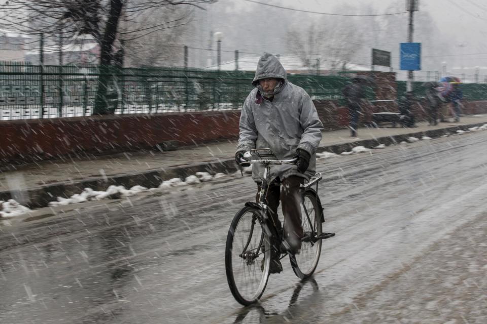 A cyclists rides as it snows in Srinagar, Indian controlled Kashmir, Saturday, Jan. 28, 2017. Authorities in Indian-controlled Kashmir have issued avalanche warnings for many parts of the region, as the heavy snowfall has cut off roads, disrupted power and communication lines, and forced the evacuation of hundreds of residents. (AP Photo/Dar Yasin)