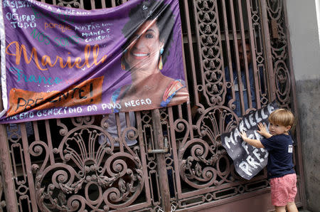 A boy holds a banner next to a picture of the Rio de Janeiro city councillor Marielle Franco, 38, who was shot dead, during a demonstration ahead of her wake outside the city council chamber in Rio de Janeiro, Brazil March 15, 2018. REUTERS/Ricardo Moraes