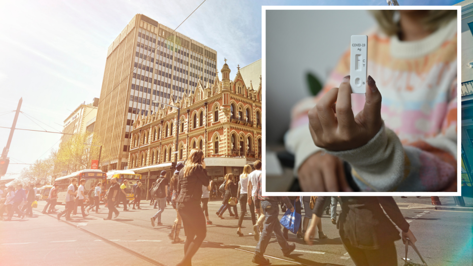 Blurred woman holds rapid antigen test, pedestrians in Adelaide. 