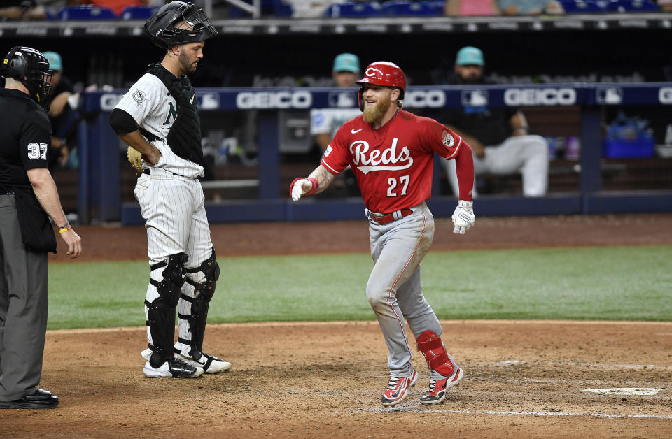 Cincinnati Reds' Jake Fraley (27) crosses home plate in front of Miami Marlins catcher Jacob Stallings during the ninth inning of a baseball game, Friday, May 12, 2023, in Miami. Fraley hit a go-ahead three-run home run. (AP Photo/Michael Laughlin)