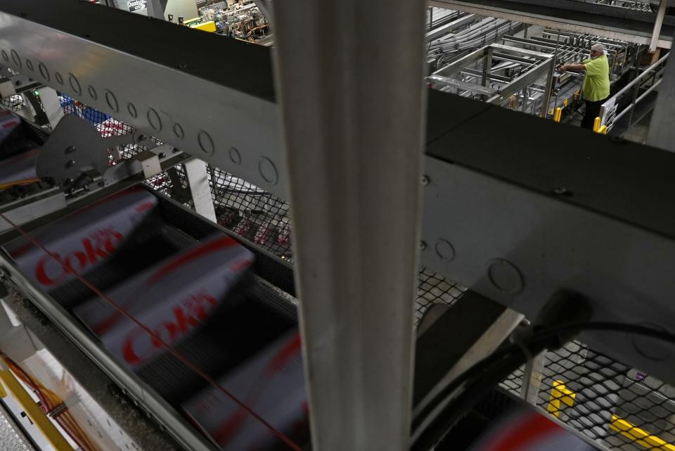 Coca-Cola cans move down a conveyer belt in the Swire Coca-Cola bottling plant Oct. 20, 2023, in Denver. Major corporations in water-guzzling industries such as apparel, food and beverage, and tech want to be better stewards of the freshwater resources they use. Coca-Cola said its water use in 2022 was about 10% more efficient compared to 2015. (AP Photo/Brittany Peterson)