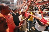 Jujubhai Bans Shrestha carries a round bamboo rack with a flaming torch as he walks around the town after getting his tongue pierced with an iron spike during the Tongue Penetration Festival at Bode near Kathmandu April 14, 2012. It is believed that after a volunteer from a Shrestha family successfully gets his tongue pierced in a spiritual trance with an iron spike and walks around the town shouldering a round bamboo rack with a flaming torch, it brings good fortune to the villagers. REUTERS/Navesh Chitrakar